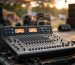 Mixer audio analog dengan fader dan knob saat soundcheck di panggung event outdoor
